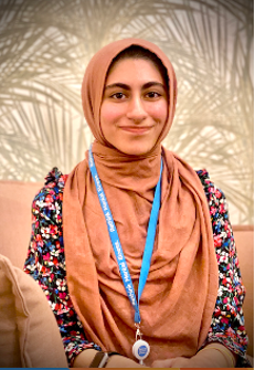 A person wearing a brown scarf and a blue lanyard
Description automatically generated